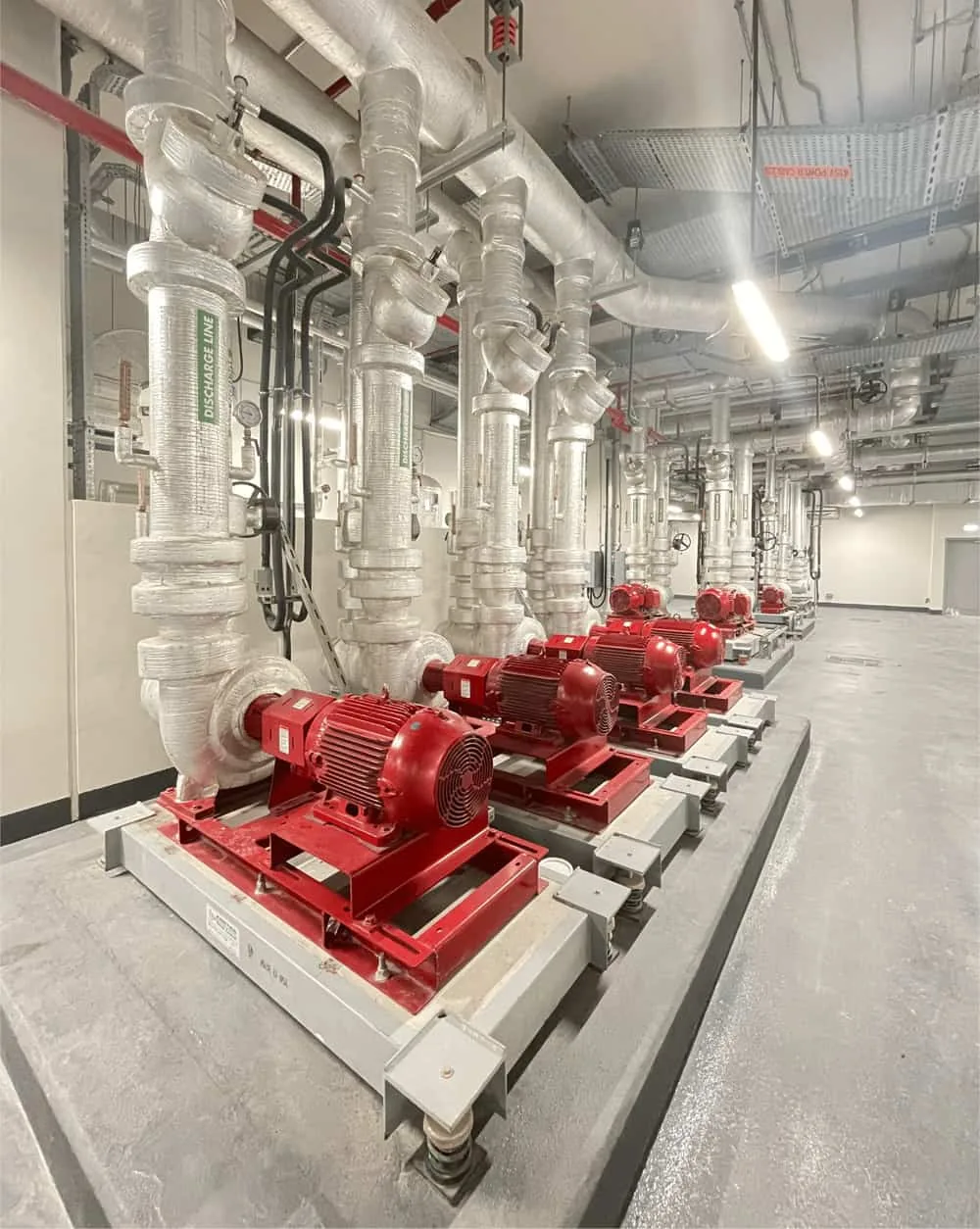 Row of chilled water pump sets on spring isolators with insulated discharge lines in a Dubai plant room